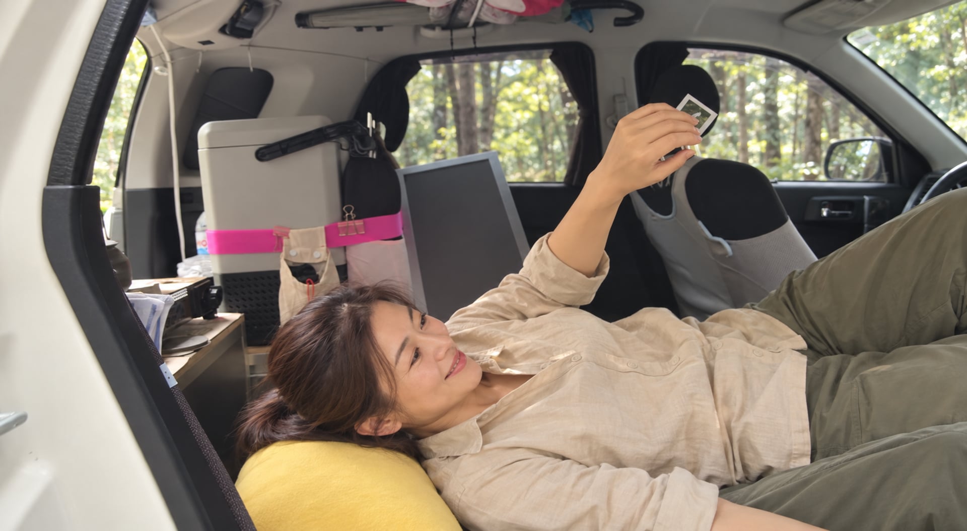 約40歲女性在車內躺臥休息，窗外森林的AI情境圖，非客戶實際出遊紀錄