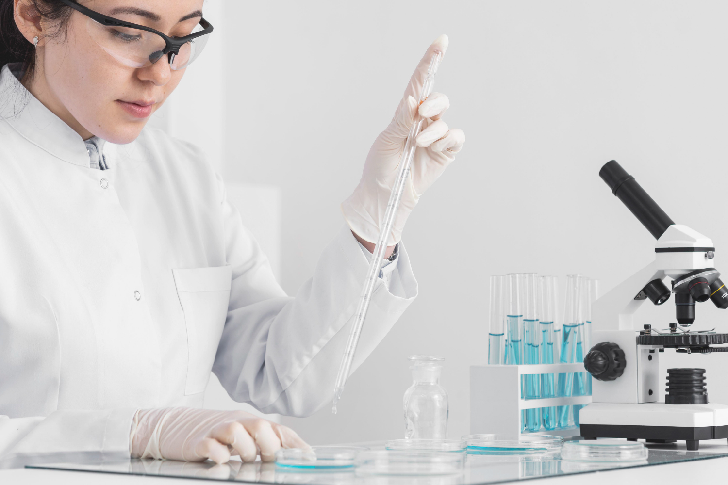 Scientist in white coat conducting skincare formulation testing in laboratory with microscope.