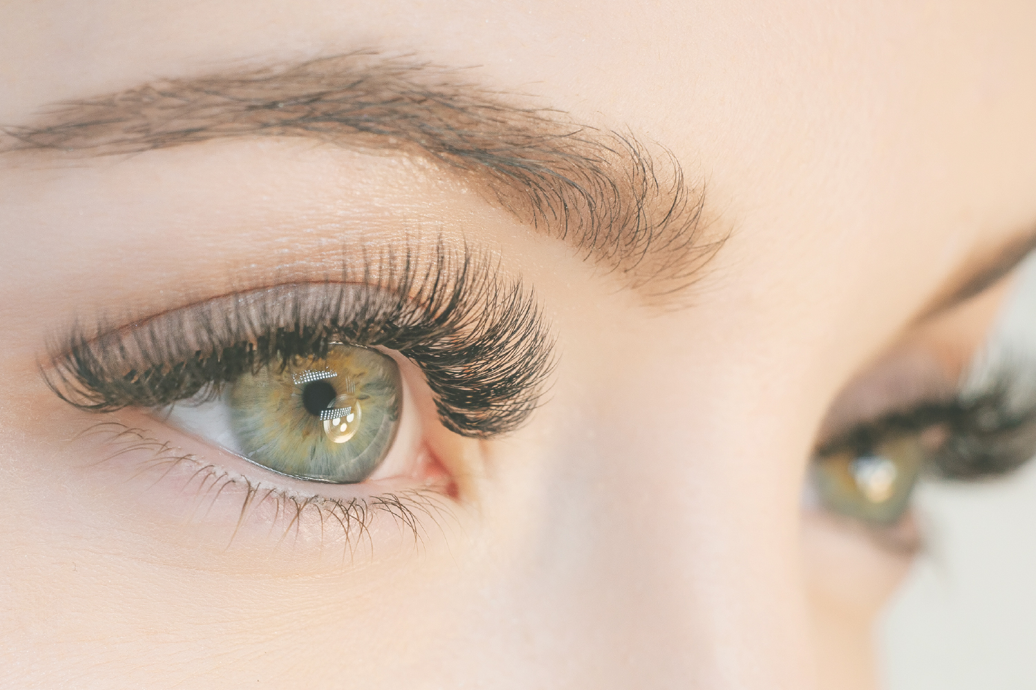 Close-up of green eyes with full eyelash extensions showing long-lasting effect