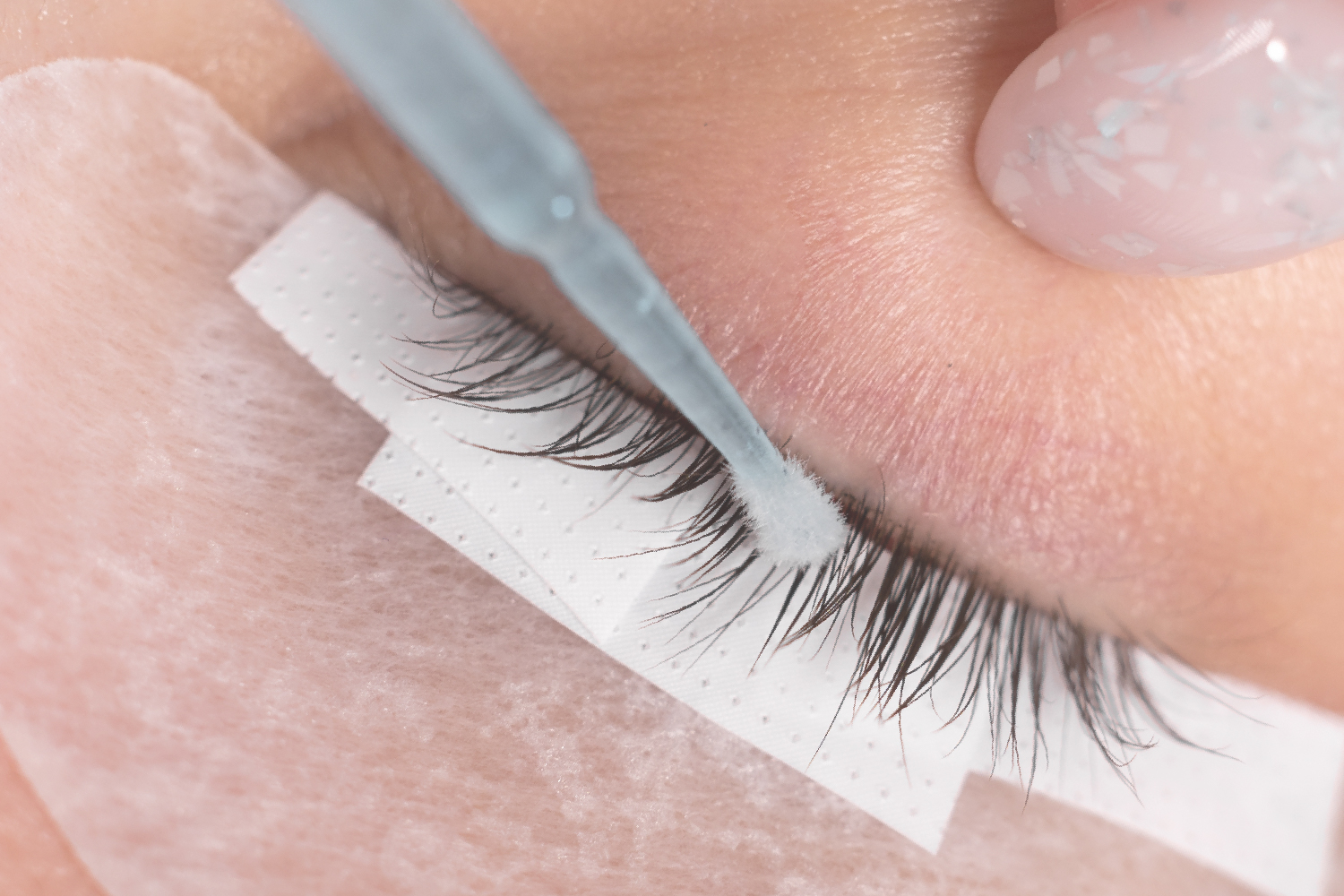 Sensitive eyelid area being treated carefully during lash application with protective tape