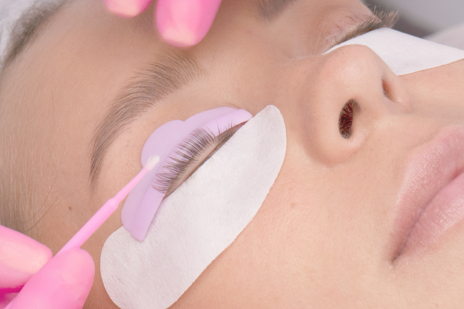 Fixing agent applied to lashes with a micro brush in the process of keratin lash setting, under-eye pads in place.