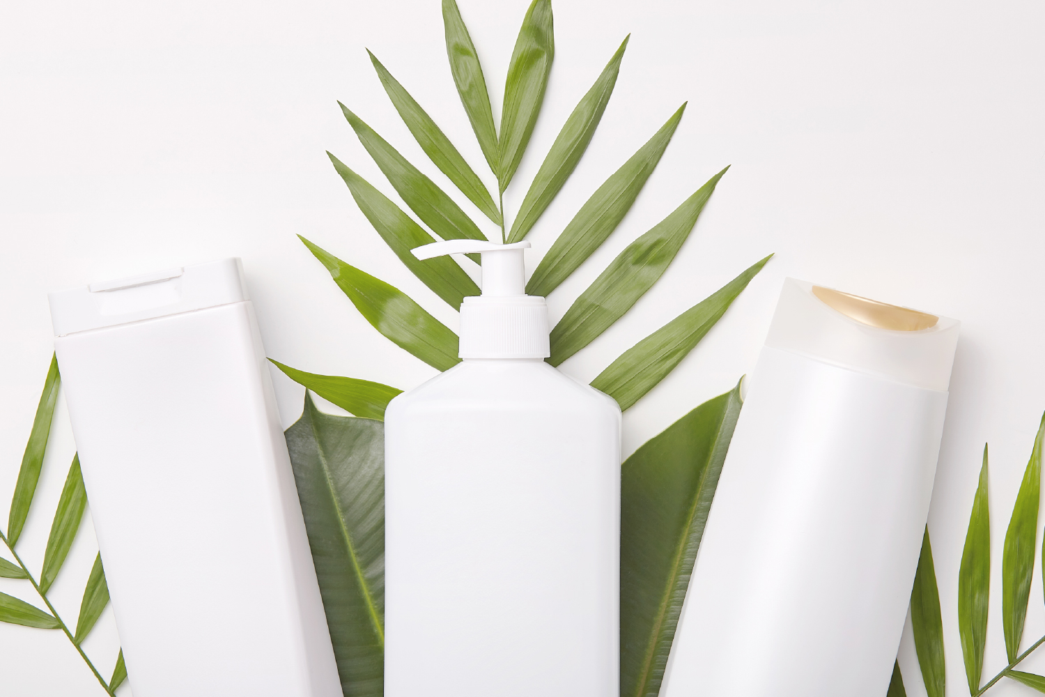 White cosmetic bottles with green leaves on background, emphasizing natural ingredients and flexible packaging options