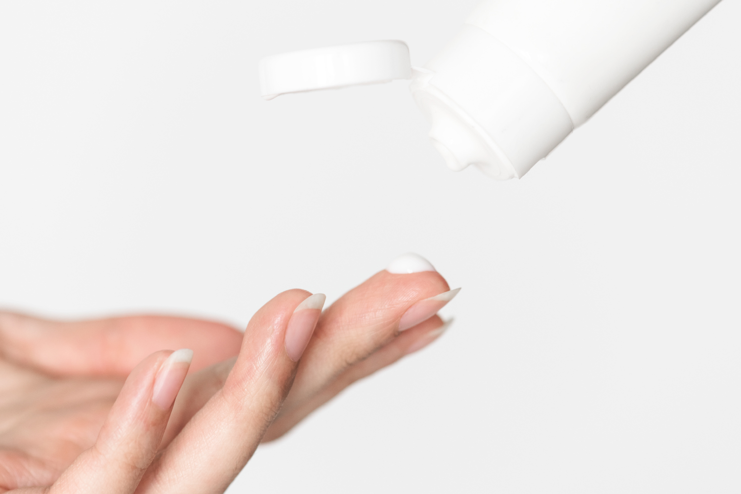 Woman applying anti-aging cream to under-eye area, highlighting deep repair benefits.